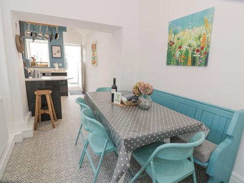 a dining room with a table and blue chairs at Swn Yr Afon in Tywyn