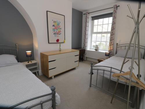 a bedroom with two beds and a dresser and a window at Swn Yr Afon in Tywyn