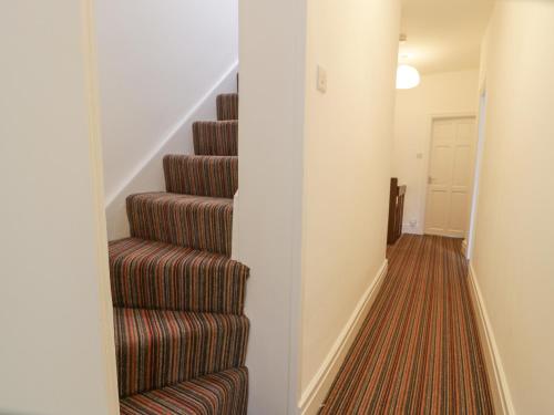 a hallway with a staircase with brown carpet at Swn Yr Afon in Tywyn