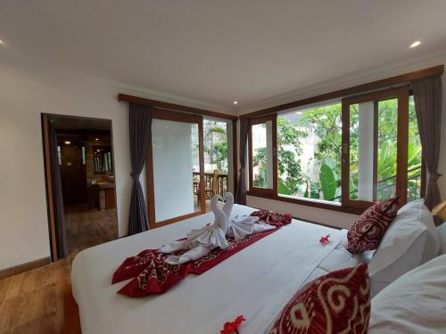een slaapkamer met een groot wit bed en ramen bij Prema Shiva Suites and Villas by EPS in Ubud
