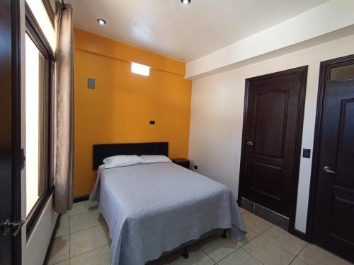 a bedroom with a bed and a brown door at Hotel Posada Lucia in San Juan La Laguna