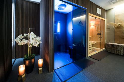 a bathroom with a shower and a vase with white flowers at HOTIDAY Room Collection - Olbia Wallure in Olbia