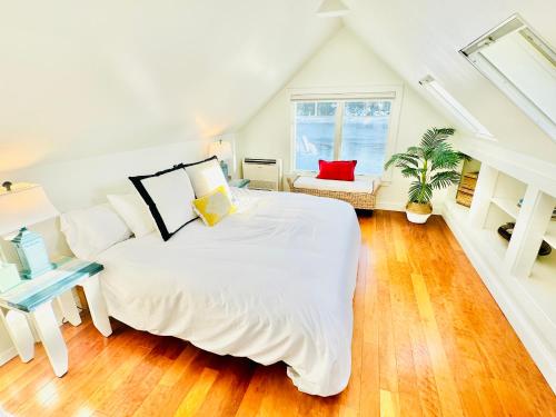 a white bedroom with a bed and a window at Cozy Cottage on the Penobscot — Panoramic Luxury! 