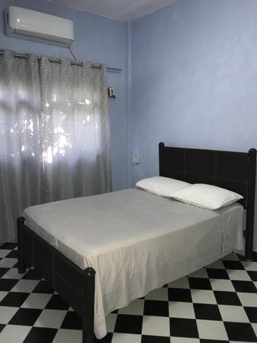 uma cama num quarto com um piso xadrez preto e branco em Ixtapa Playa Linda Hostel em Barrio Nuevo