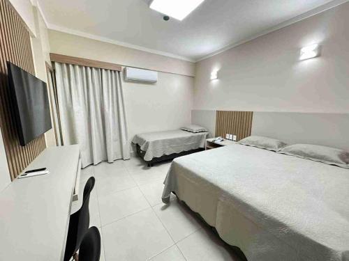 a hotel room with two beds and a flat screen tv at Spazzio diRoma com acesso ao Acqua Park - Adriele in Caldas Novas