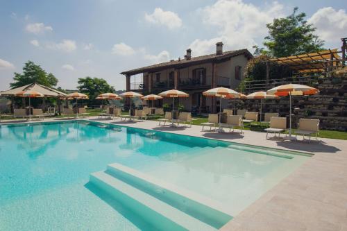 une grande piscine avec des chaises et des parasols dans l'établissement Agriturismo Camponovo, à Brisighella