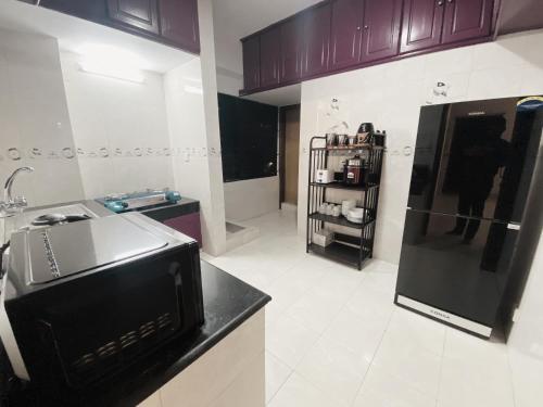 a kitchen with a sink and a black refrigerator at Amazing Apartment in Bashundhara in Dhaka