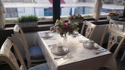 een witte tafel met een vaas met bloemen erop bij Karavan in Yakkasaray