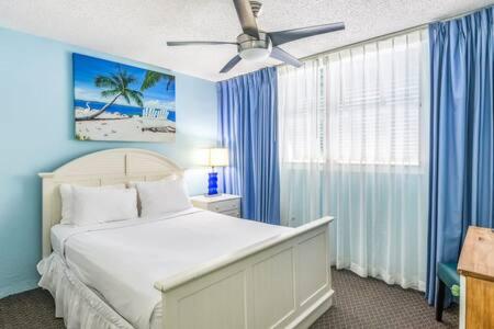 a bedroom with a bed with blue walls and a ceiling fan at The Trinidad by Brightwild-Pool & Parking in Key West