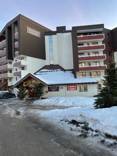 un grand bâtiment avec de la neige devant lui dans l'établissement logement chaleureux 1 chamb pied des pistes, à Huez
