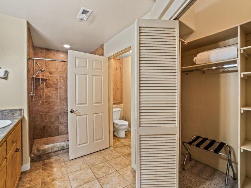 a bathroom with a shower and a toilet and a door at Rim Village X3 - large patio with private hot tub in Moab
