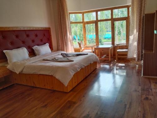 a bedroom with a large bed with a red headboard at Zee Guest House in Leh