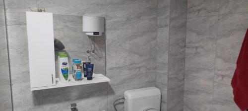 a bathroom with a white toilet and a marble wall at Aura City 2 in Visoko