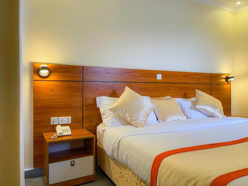 een hotelkamer met een bed met een houten hoofdeinde bij Standard Single Room At Amikus Hotel in Gasanze