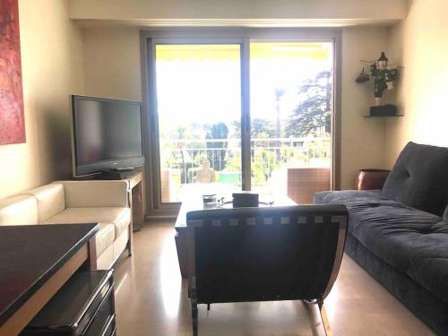un salon avec un canapé et une télévision dans l'établissement BEL APPARTEMENT-PROCHE MER-TERRASSE, à Cannes