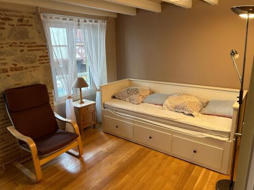 a bedroom with a bed and a chair and a window at Coeur de Bastide in Villeneuve-sur-Lot