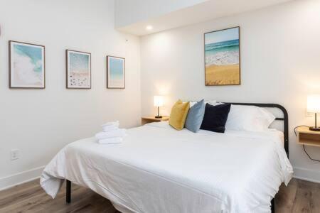 a bedroom with a white bed with pictures on the wall at Ocean Lofts in the Vibe #8 - 5 min walk to beach in Virginia Beach