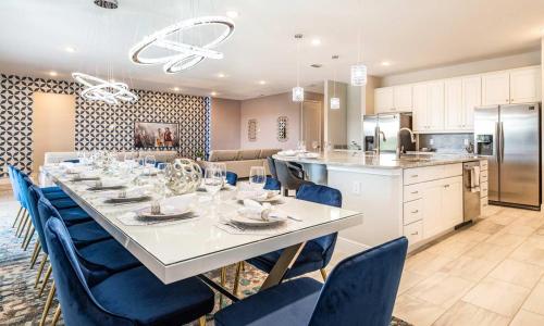 a kitchen with a long table and blue chairs at Gleaming 12 Bdrm Villa With Themed Bedrooms at Encore in Orlando