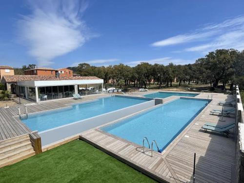 une grande piscine avec une terrasse en bois à côté dans l'établissement Mini Villa 4-6 pers. Les hameaux de Saint Cyprien, à Lecci