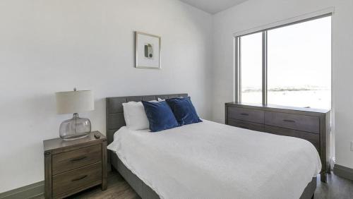 Un dormitorio con una cama con almohadas azules y una ventana en Landing Modern Apartment with Amazing Amenities (ID1381X635), en The Colony