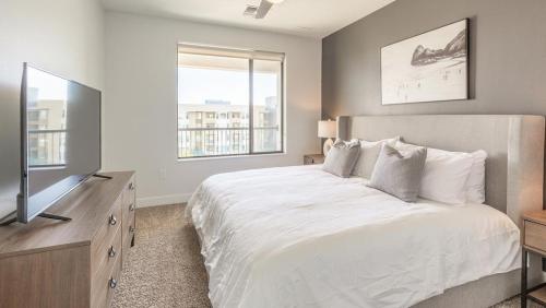 1 dormitorio con 1 cama blanca grande y TV en Landing Modern Apartment with Amazing Amenities (ID7740X83), en Tempe