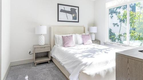 a white bedroom with a bed with pink pillows and a window at Landing Modern Apartment with Amazing Amenities (ID1011X798) in San Antonio