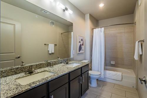 y baño con 2 lavabos, aseo y bañera. en Landing Modern Apartment with Amazing Amenities (ID5227) en Houston