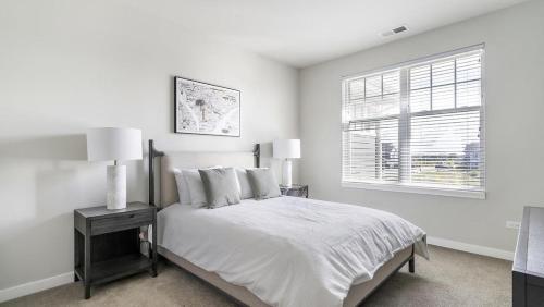 um quarto branco com uma cama e uma janela em Landing Modern Apartment with Amazing Amenities (ID1209X830) em West Dundee