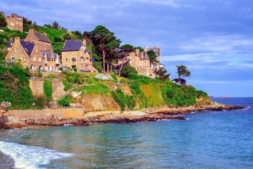 a group of houses on a hill next to the ocean at ch'ty breizh in Perros-Guirec
