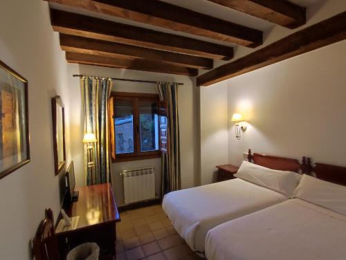 a hotel room with two beds and a window at Hostal Posada La Panadera in Sepúlveda