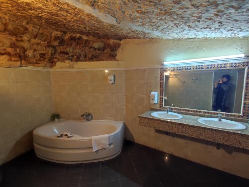 a bathroom with a tub and two sinks and a man taking a picture at Hostal Posada La Panadera in Sepúlveda