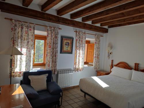 a bedroom with a bed and a chair and a table at Hostal Posada La Panadera in Sepúlveda