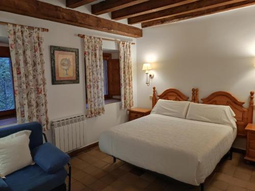 a bedroom with a bed and a blue chair at Hostal Posada La Panadera in Sepúlveda