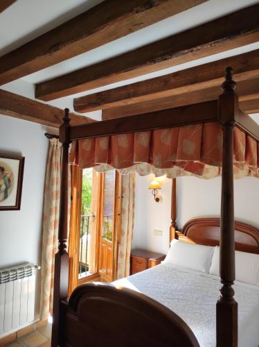 a bedroom with a canopy bed and a window at Hostal Posada La Panadera in Sepúlveda