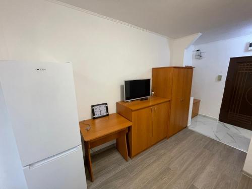 a room with a desk with a tv and a refrigerator at Apartament cu o camera in Oradea