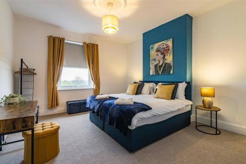 a bedroom with a large bed with a blue headboard at Affordable luxurious 3 bedroom 3 bathroom house great for contractors and large groups within 1 mile to City Centre with free parking in Nottingham