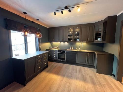 cocina con armarios negros y suelo de madera en Rjukan Sentrum Apartments NO 1 en Rjukan