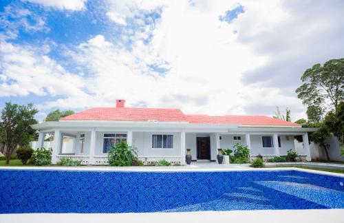 a white house with a red roof and a swimming pool at African Oak: Rosewood in Arusha