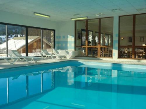 a swimming pool with chairs and a building at Chalet de 3 chambres a Le Devoluy a 200 m des pistes avec piscine partagee sauna et balcon in Le Dévoluy