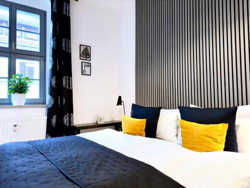 een slaapkamer met een bed met blauwe en gele kussens bij Hip & Minimalist meets Historical Old Town in Pirna