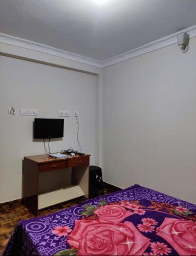 a bedroom with a bed and a desk and a tv at Relaxzen Homestay 2 in Kodaikānāl