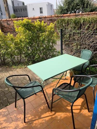 - une table verte et 2 chaises sur la terrasse dans l'établissement L’Eden Studio Suite Balneo plein centre d’Andernos, à Andernos-les-Bains