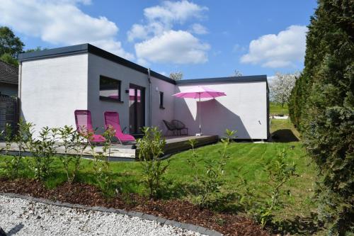 a small house with pink chairs and an umbrella at Naturgeflüster Chalet in Morbach