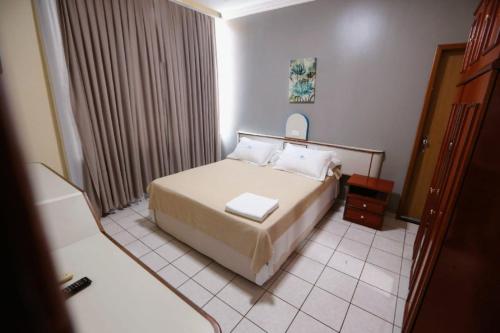 Habitación de hotel con cama y espejo en SERRA AZUL PLAZA HOTEL, en Barra do Garças