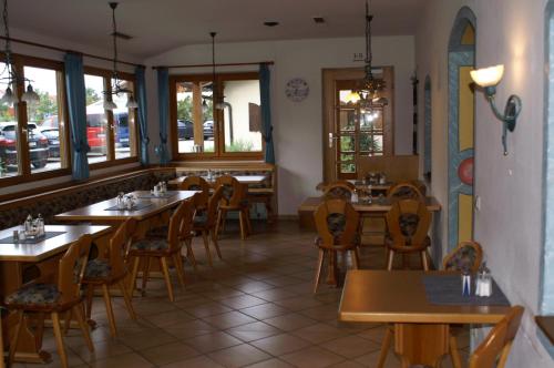 um restaurante com mesas e cadeiras de madeira e janelas em Scharmerhof em Hohenbrunn