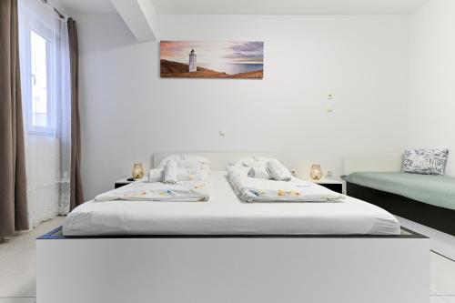 a white bedroom with two beds and a lighthouse at Apartments Villa Visnjik in Zadar