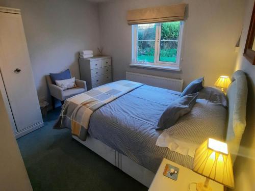 a bedroom with a bed and a chair and a window at Cwmwdig Cwtch (3 minutes drive to Abereiddy bay!) in Haverfordwest