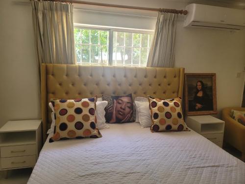 a bedroom with a large bed with pillows and a window at Royal Eagles in Gaborone