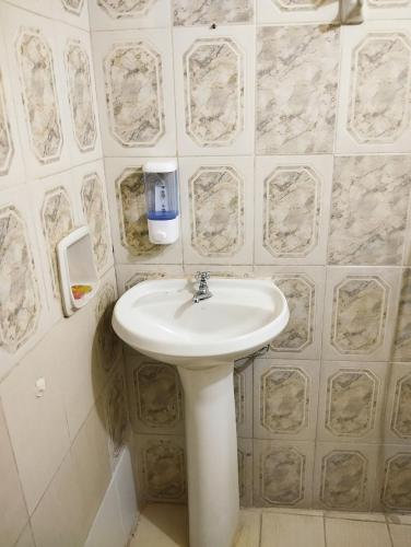 La salle de bains est pourvue d'un lavabo blanc et de carrelage en marbre. dans l'établissement Mangoty Apartamento, à Luque