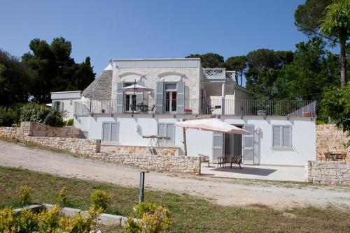 a white house with an umbrella and a table at Villa Rosato in Selva di Fasano